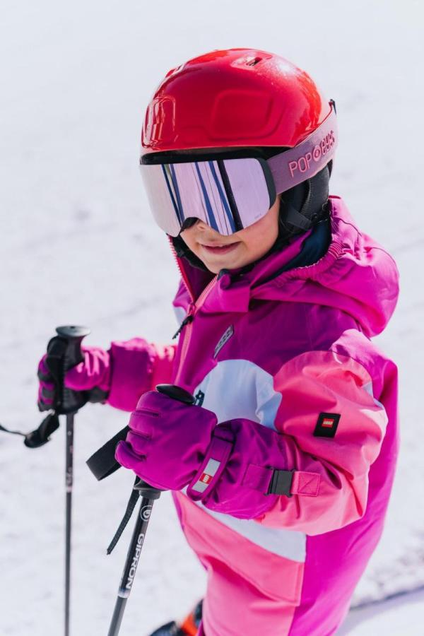 Barn med skihandsker, hjelm og skibriller.
