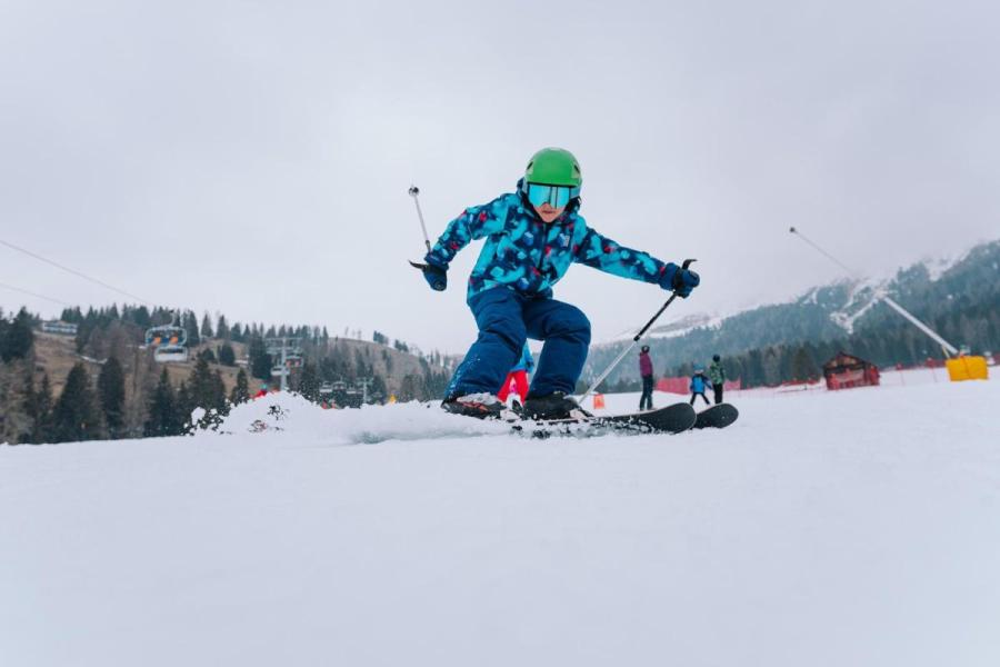 Barn står på ski på en sneklædt piste.
